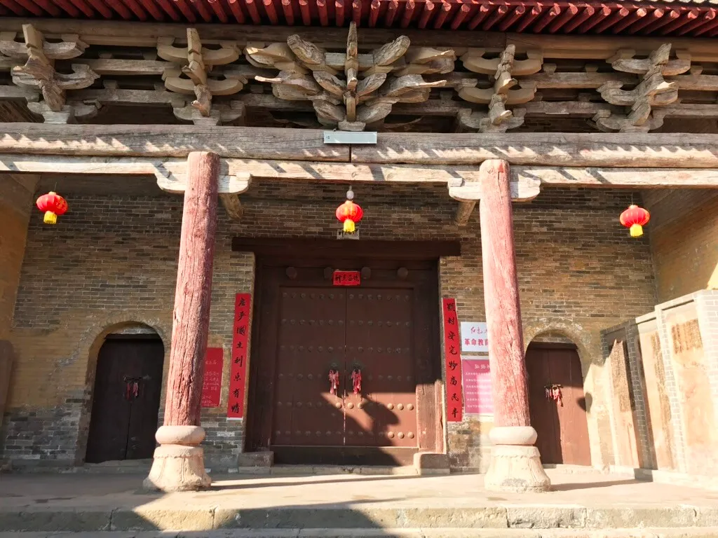 殿宇檐下的木构斗栱和额枋，下方是两根石础木柱